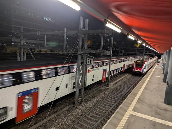 Un Léman Express quitte la gare de Sécheron pour Coppet et se fait doubler par un IC2000 sur sa gauche.