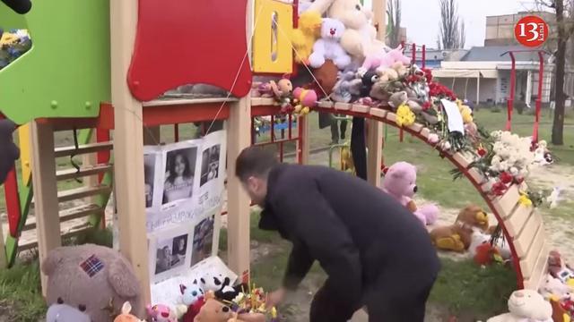 President Zelenskyy places a teddy bear underneath pictures of the children killed by a Russian missile.