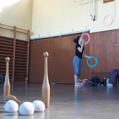 Une jongleuse anneaux, en arrière-plan, et des massues et balles en vrac, sur le sol, pendant le précédent stage de jonglage à Chenôve !