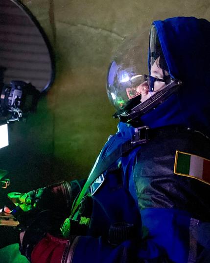 Me wearing a blue spacesuit inside a spacecraft simulator. The italian flag is on the spacesuit
