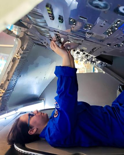Me wearing a blue flight suit inside the Apollo spacecraft simulator