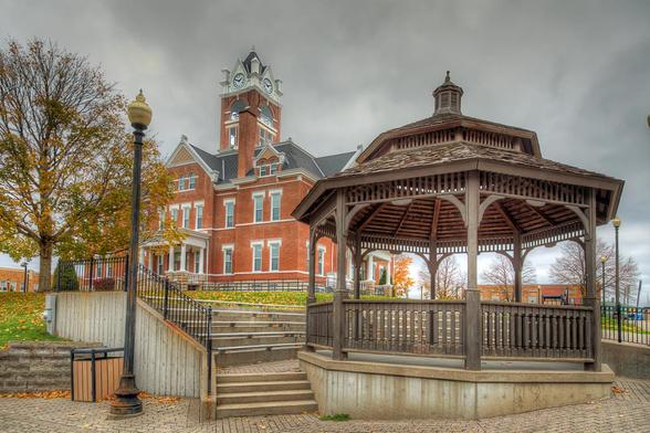 A striking red-brick building with a clock tower stands against a cloudy sky, 