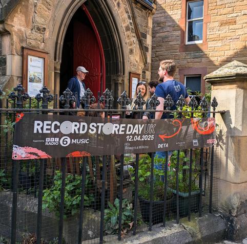 A banner reading "record store day UK" on a fence in front of a church