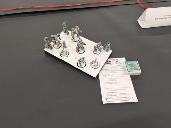 A snow covered diorama with 5 mechs in Clan Jade Falcon Gamma Galaxy colours with winter camouflage and 2 squads of Elemental battle armour infantry.  A small plaque reads "IPMS Victoria Gold".  A Sign reads "Figure Diorama C15) Diorama (More tha..." and is cut off