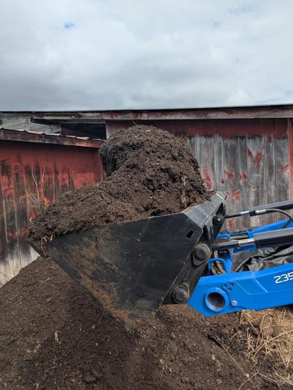 Tractor Bucket of compost holding on in physics defying ways. (It's just a big frozen chunk)