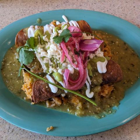 Chicken taquito ahogado, served in salsa verde with Spanish rice, avocado crema, sour cream, pickled onion, cotija, and cilantro.