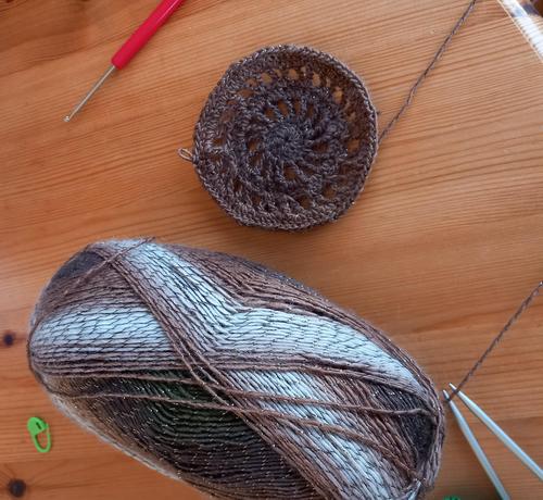 Une pelote de laine et un disque au crochet dans les tons marron