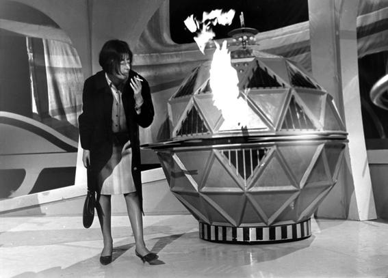 14th April, 1965: Legendary Doctor Who producer Verity Lambert confronts a flame-belching Mechanoid at Ealing Studios, London... and lights her ciggy with it.