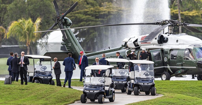 Picture of Trump with a red MAGA cap, walking from a big helicopter to a golf cart
There's 4 golf carts, a lot of bodyguard, and military personnel in full regalia..