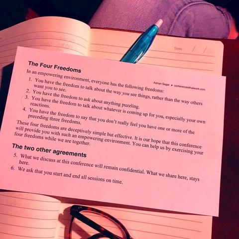 The fairest rules for meetings. Photograph of a card showing the six rules Adrian Segar uses for meetings: The Four Freedoms and two other agreements. The card is laying on a notebook, together with a pen and glasses.