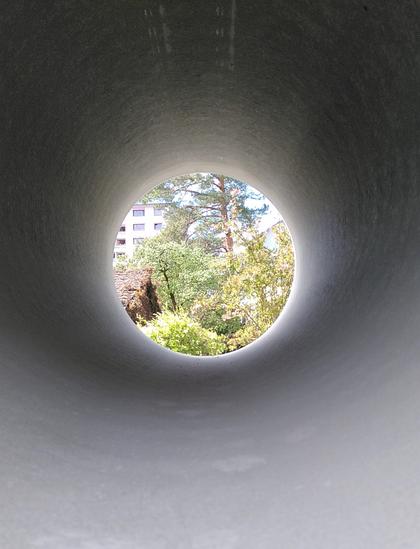 Tunnelblick durch eine riesige Betonröhre. Auf Büsche und Bäume. 