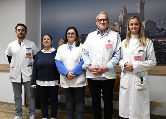 Équipe médicale pluridisciplinaire de l’APHM (services d’hématologie et de médecine vasculaire) posant dans un couloir hospitalier, avec en fond une grande photo de Notre-Dame-de-la-Garde.