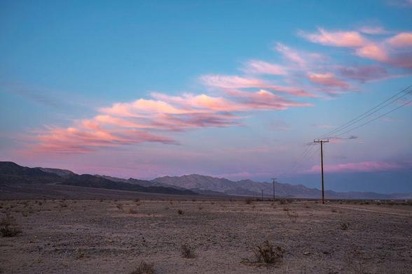 Clouds in linear formation at sunset over desert landscape with power poles.