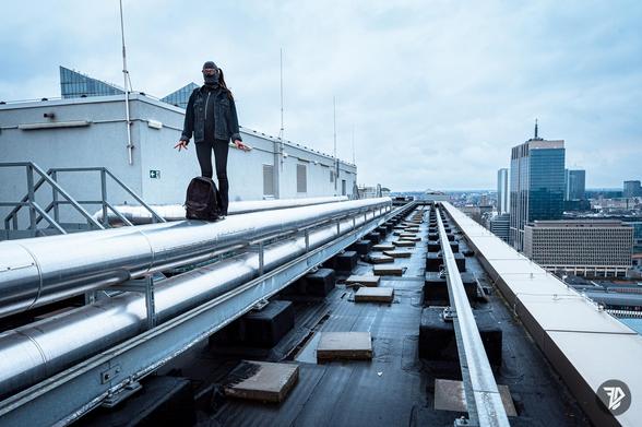 silhouette of a girl standing on the rooftop of a tall building with great perspectives lines of the pipes on the roof