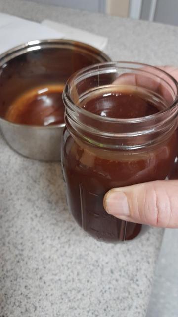Amazing jar full of chocolate syrup with an empty Pan behind it