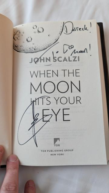 The interior title page of John Scalzi's When The Moon Hits Your Eye novel signed by the author, dedicated to Derreck.