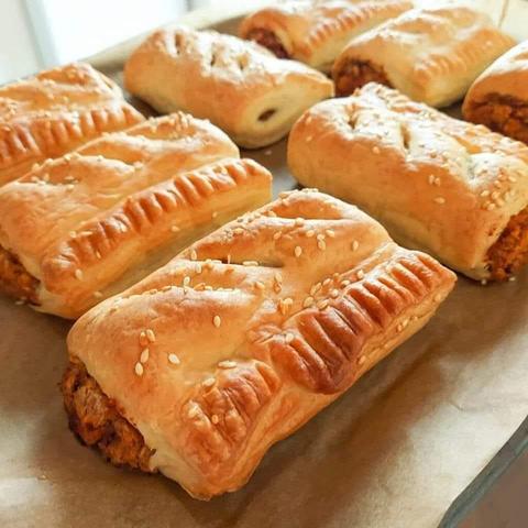 A tray of just out of the oven  golden and flaky puff pastry sausage rolls with a spicy chickpea filling.