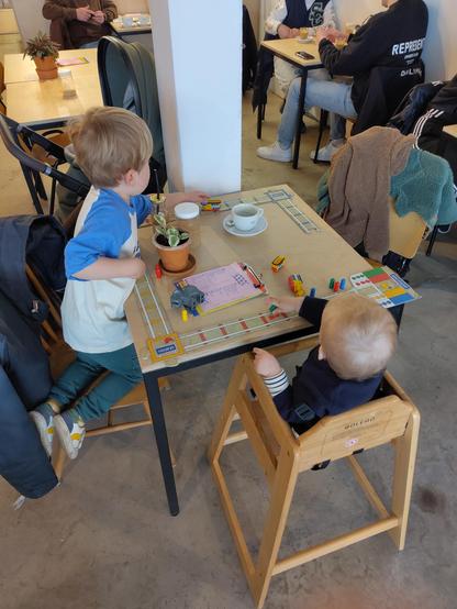 Twee kleine kinderen in restaurant aan tafel aan het spelen.