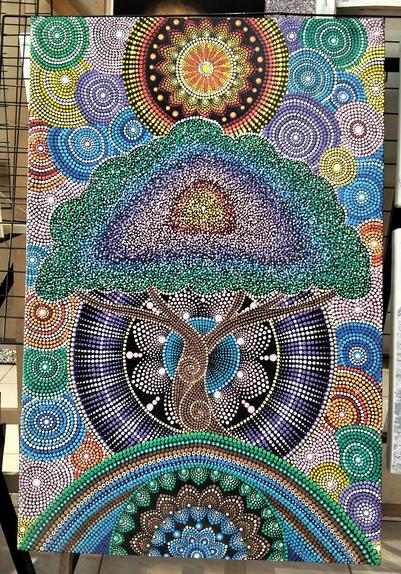 a painting of a psychedelic tree with mandalas swirling behind it, colored wheels of all different tones in the sky  the painting is done in small dots of paint 