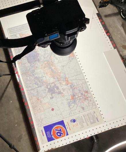 A document scanning setup in a basement —an illuminated map on a low platform, with a camera on a boom overhead