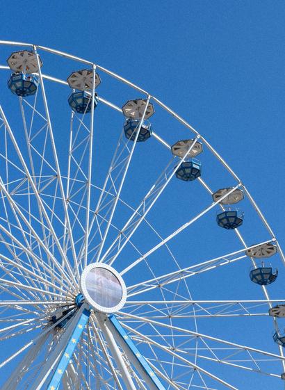 Ferris wheel with blue carriages in a blue sky