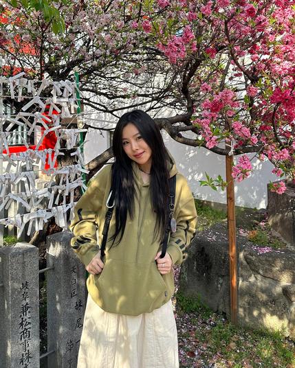 photo of wheein under a blooming tree. cherry blossom?