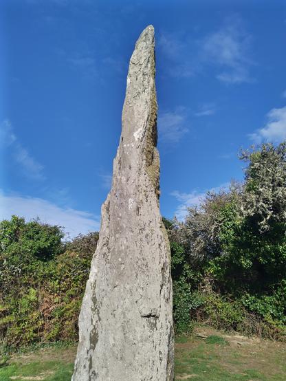 Un menhir très haut et très effilé de l'Ile de Groix, un jour de ciel bleu.
