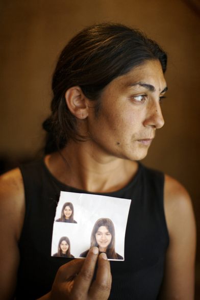 Woman holding an image to the camera of a younger woman looking to the side