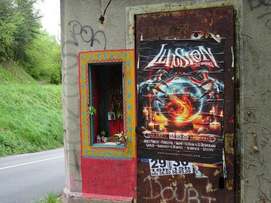 En bord de route, dans une ancienne cabane de cantonier, la fenêtre murée a été transformé en oratoire bouddhiste : frises turquoise, jaunes et rouges, guirlandes de feuillages et fleurs en plastique, petits objets divers (un preservatif bien emballé, des bougies à piles, des cailloux) et affichettes dont une qui tente de faire la leçon aux voleurs de bouddhas et d'autres plus politiques les femmes n'ont pas eu le droit de vote en votant, les policiers sont stupéfiants, etc. A coté a été collée une grande affiche annonçant un festival de magie dont le titre est Illusion : une boule de feu tenue par des mains griffues..