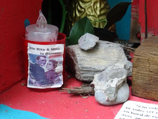 le gobelet dans lequel trône une bougie est étiqueté ste rita et nina la démone, nom d'un duo de chanson française local.