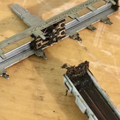 A close-up view of a disassembled slide potentiometer fader, taken out of a Marantz PMD 740 multitrack cassette recorder for cleaning. The residue and debris that had built up on the track and in the wipers of this fader almost has the consistency of mud.