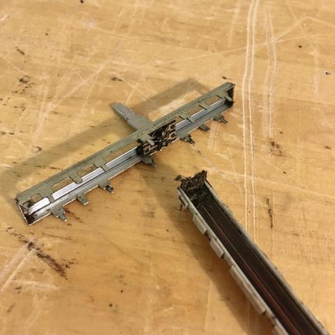 A disassembled slide potentiometer fader taken out of a Marantz PMD 740 multitrack cassette recorder for cleaning. The residue and debris that had built up on the track and in the wipers of this fader almost has the consistency of mud.