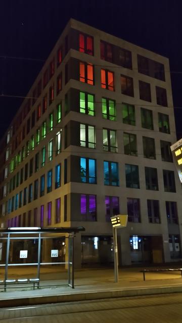 Office building in Berlin Mitte at night;
All rooms at one side of the building are illuminated in different colors per floor: 🏳️‍🌈
First floor purple 
Second floor blue
Third floor greenish
Fourth floor green
Fifth floor orange 
Sixth floor red
(not sure if permanently or temporarily)