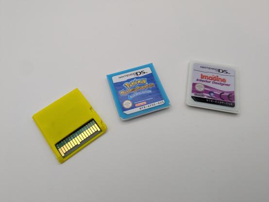 3 ds lite carts fanned out on a white background, from left to right, yellow shell layed face down, the blue cart "pokemon mystery dungeon" and a white one "imagine interior designer" 