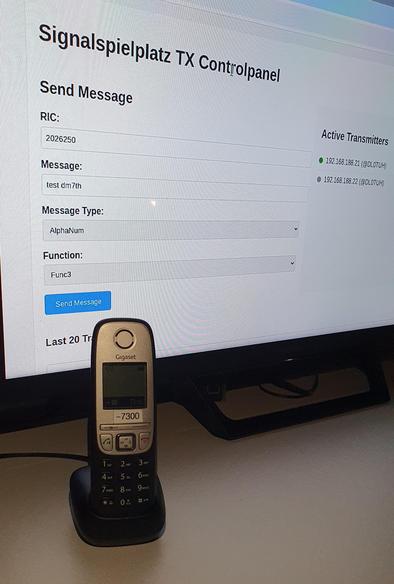 Photo of a pager control panel on a screen, in front of it a phone.
