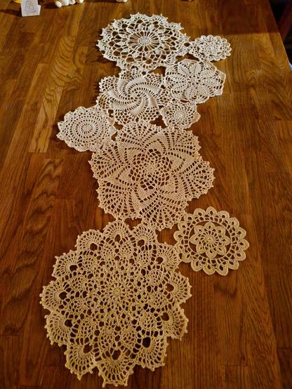 Several white doilies,several shapes and sizes, sewn together to make a tablerunner