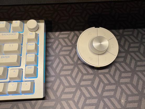 The round, white, wireless shortcut puck for the BenQ PD2730S monitor. Multiple buttons arranged in a ring around a silver knob. 