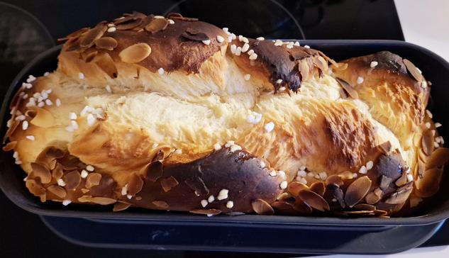 Ein schön aufgegangener, oben etwas eingerissener, Hefezopf. Bestreut mit Mandelplättchen und Hagelzucker.