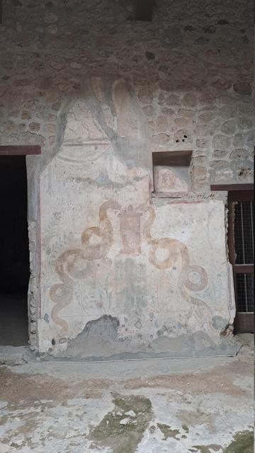 Photo of a Pompeii Roman wall painting of two coiled snakes one on each side of a pillar or fountain, which they might be eating or drinking out of
