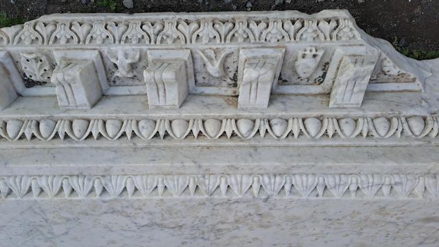 Photo of a Pompeii Roman marble carving example with very fine details of flower and leaf and other patterns all apparently intricately carved into the layers and shapes of the single massive block