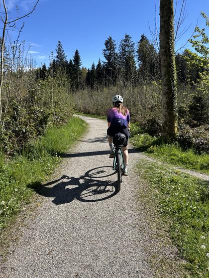A woman riding on a gravel path through the forrest