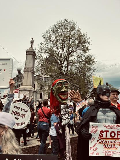 protesters, including Batman, holding pro-democracy signs and a big green puppet head
