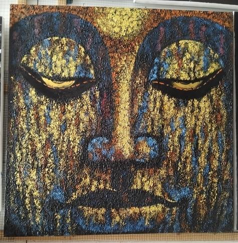 a face, the eyes low  in meditation, it is gold with some blue in it, lots of texture to it 