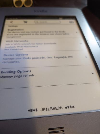 Kindle e-reader with **** JAILBREAK **** across the bottom.
