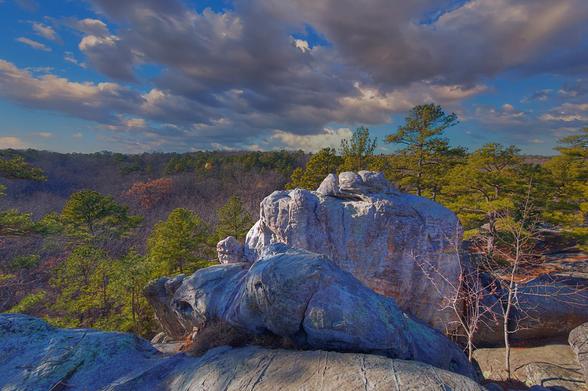 Rugged rocks and vibrant green trees are illuminated by the sunlight,