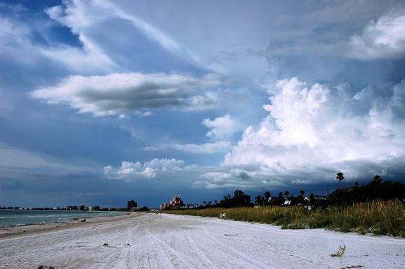 Storm clouds approaching a beach with the sea to the left and a line of sea oats on the right