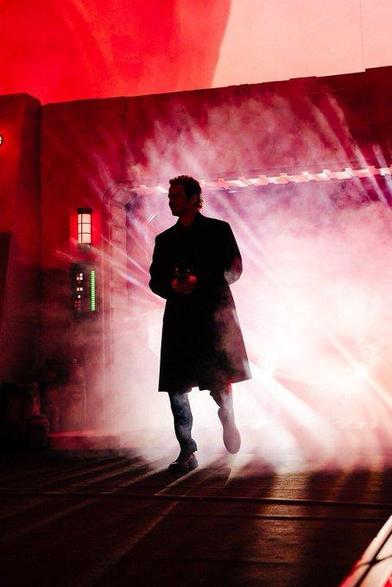 Hayden Christensen in Japan at Star Wars Celebration. He's a black shadow against red light with steam behind him. Very Darth Vader coded.