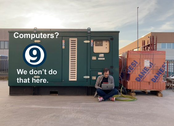 big power generator plan 9 logo and written: "computer? We don't do that here" on the side seated on the ground a man with a laptop charging plugged into the generator