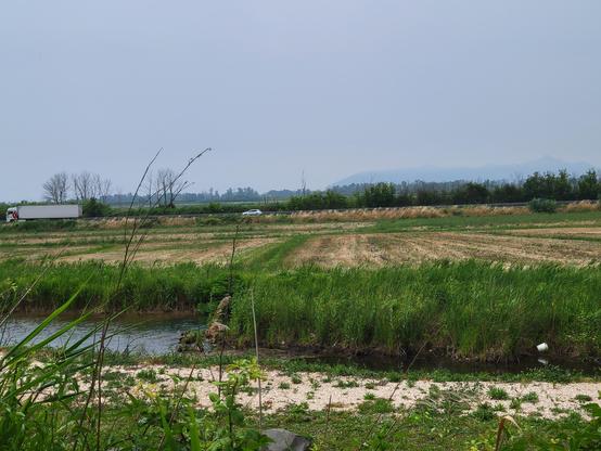 View from ancient shrine across a plain of cultivated farmland with the outline of Cape Circeo visible in the distance
