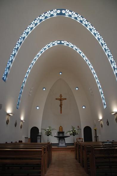 Interior view from near the entrance towards the altar. The arched glass windows overhead are a striking feature of this church.